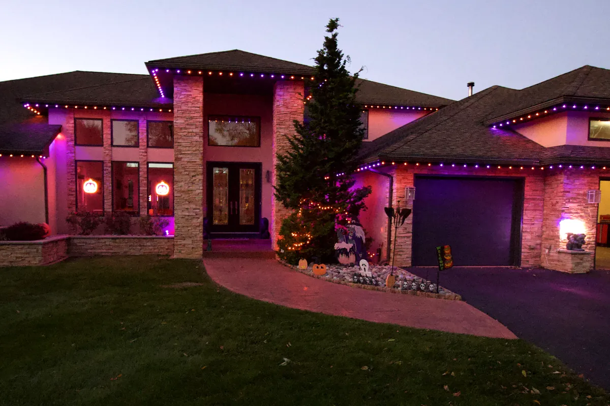 The same home at dusk with Trimlight lights on in purple and orange for Halloween